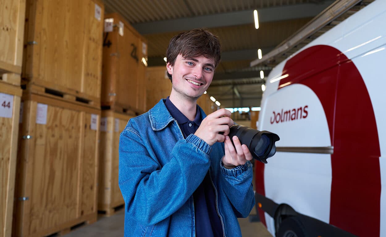 Martijn van de marketingafdeling van Dolmans bezig met fotografie in het magazijn naast bedrijfswagen